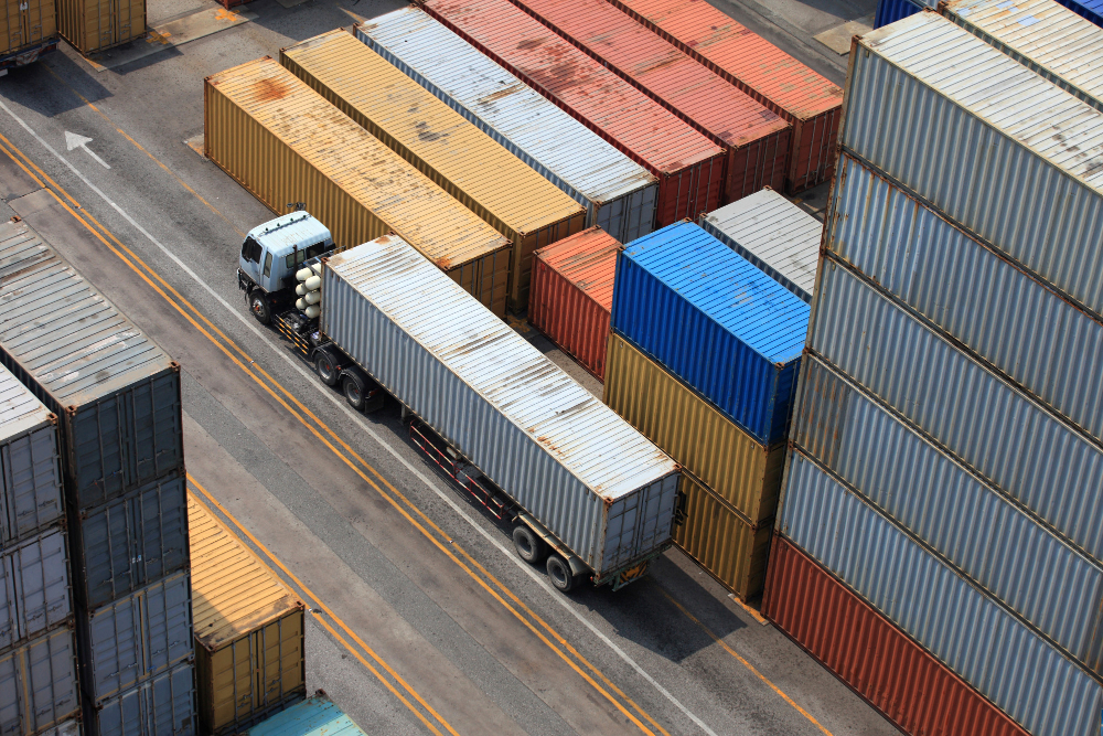 Aerial view of a truck navigating through rows of colorful shipping containers, highlighting container storage and logistics services. 